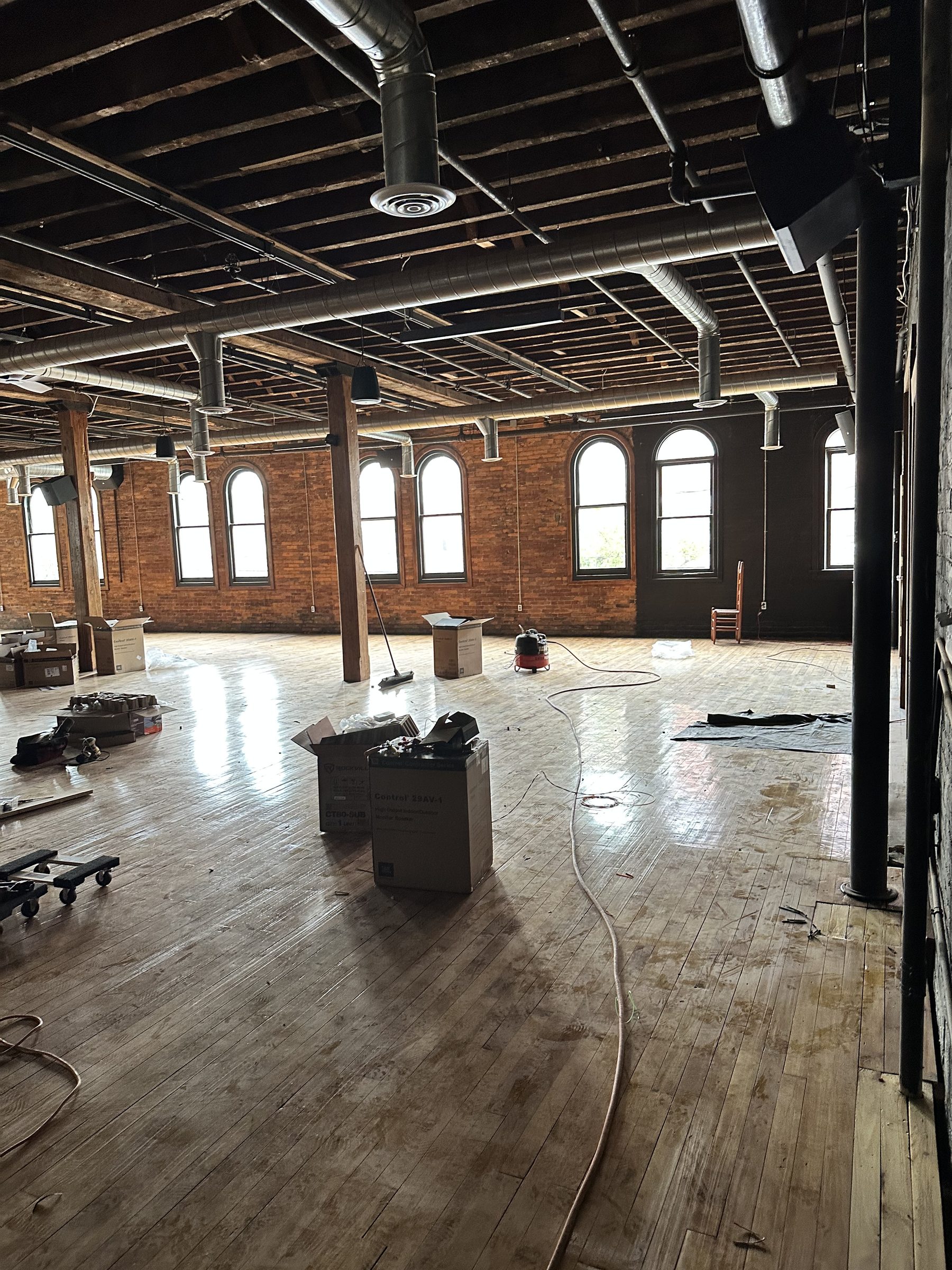 The hall's long wall of tall arched windows in exposed red brick